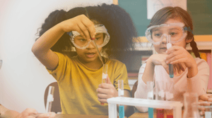 Girls with eye protection placing liquid in test tubes