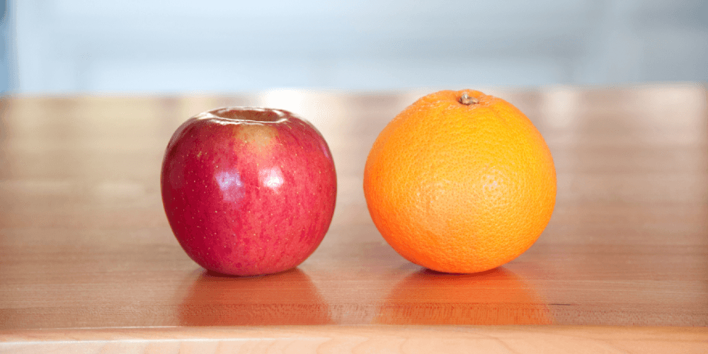 an apple and an orange on a wooden table