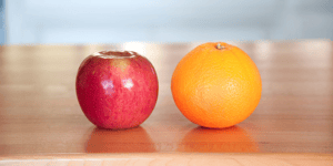 an apple and an orange on a wooden table