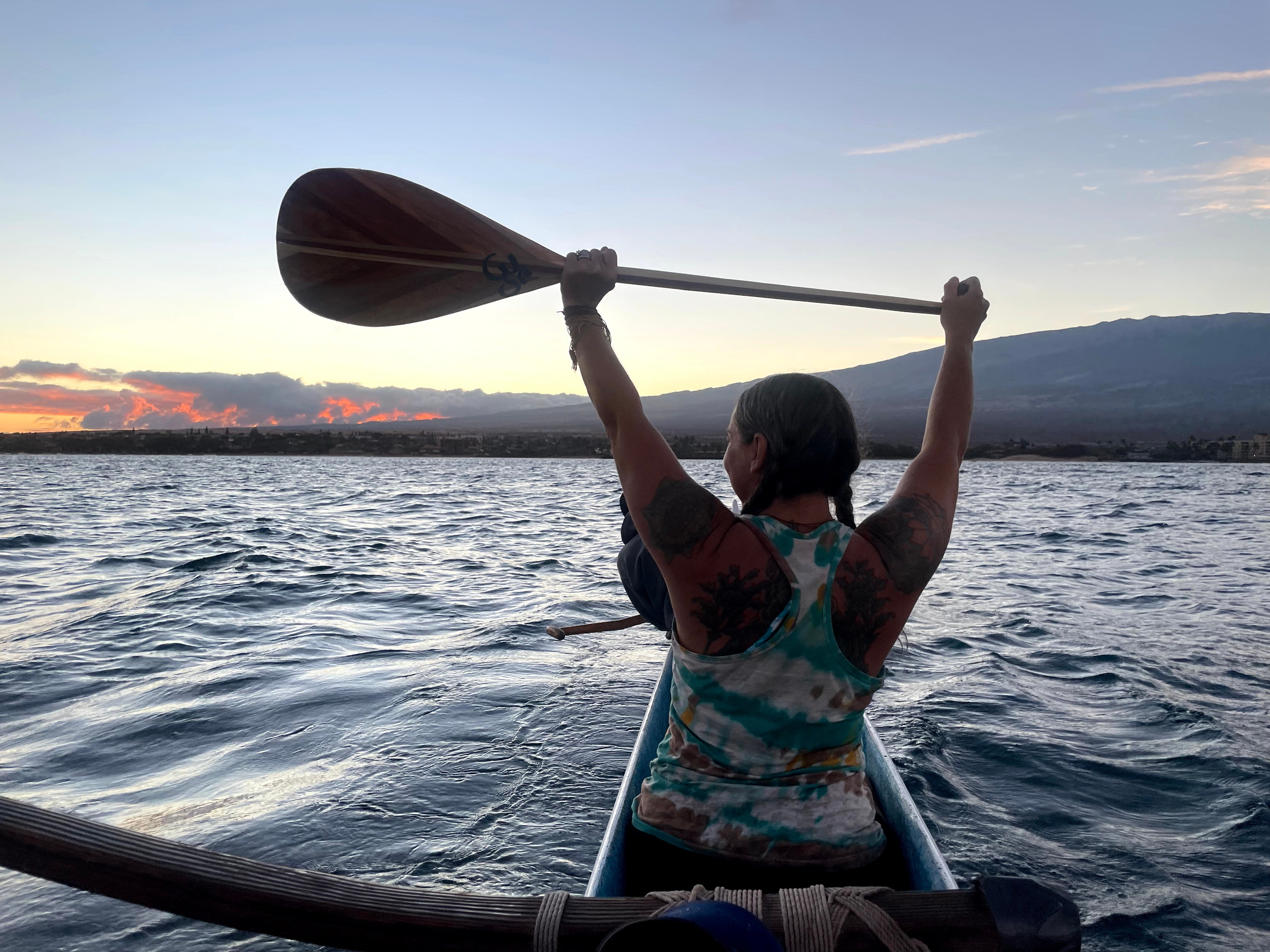 Allison Chaney holding a paddle over her head in a canoe in Hawaii