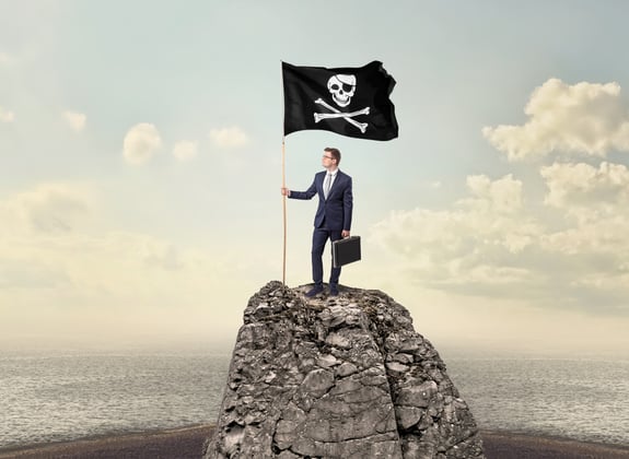 Successful businessman on the top of a mountain holding pirate flag